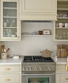 a stove top oven sitting inside of a kitchen next to white cupboards and counter tops