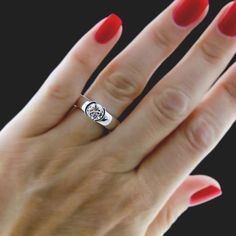 a woman's hand with red nails and a ring on it