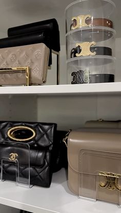 several different purses are on shelves in a closet with clear bins and plastic containers