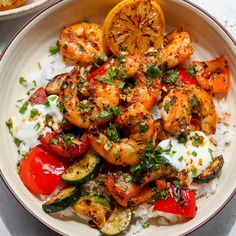 a white bowl filled with shrimp, rice and veggies on top of a table