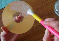 a person holding a pink and yellow toothbrush next to a cd on a table