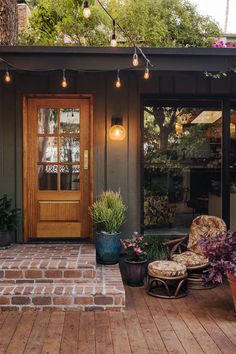 the front porch is decorated with potted plants and hanging lights over the entrance door