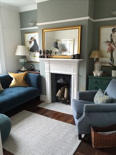 a living room with two blue couches and a white rug on the floor in front of a fireplace