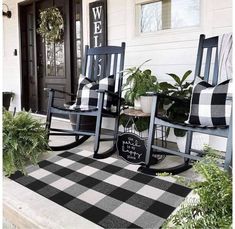 two rocking chairs on the front porch with black and white plaid pillows, potted plants and welcome sign