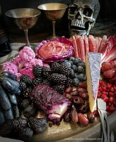 a table topped with fruits and vegetables next to a skull head on top of it