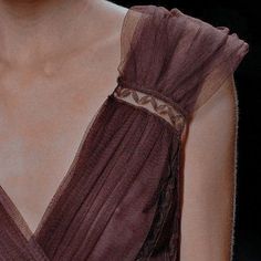 a close up view of a woman's neck and shoulder, wearing a brown dress