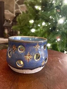 a blue bowl sitting on top of a wooden table next to a christmas tree in the background