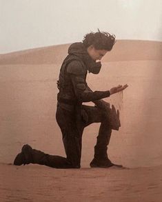 a man kneeling down in the middle of a desert