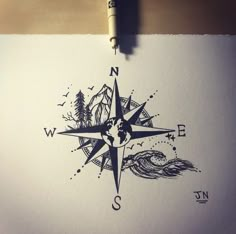 a drawing of a compass with trees and waves in it on top of a piece of paper