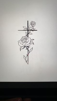 a cross with three roses on it and a hand holding the cross in front of it