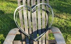 a heart shaped metal sitting on top of a wooden chair in the middle of grass