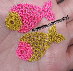 two small crocheted fish sitting on top of each other in someone's hand