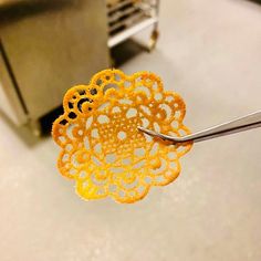 a pair of scissors cutting yellow crochet doily on a machine in a kitchen