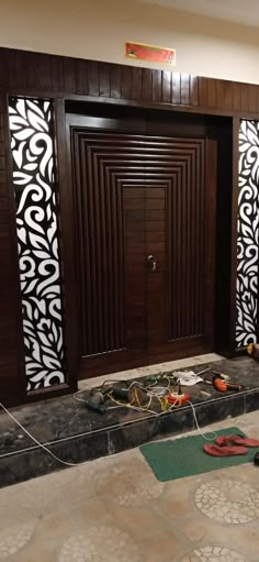 a pair of red shoes sitting on the floor in front of a wooden door with decorative panels