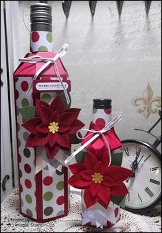 two wine bottles are decorated with poinsettis and ribbons for the holiday season