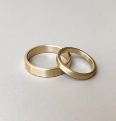 two gold wedding rings sitting on top of each other