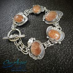 "Glistening sunstones with great shimmer! --picture doesn't do it justice-- set in a hand fabricated sterling and fine silver bracelet. Each segment has a varying design with a hand forged leaf and a swirling vine or two. Each is connected by two heavy guage, hand formed soldered links, ending at a toggle clasp with leaf motif on the top (see photo). Makers mark and silver quality stamp on reverse side. This is an heirloom quality piece. The stones are all natural and imperfect, with highly aven Forged Leaf, Sunstone Bracelet, Leaf Motif, Toggle Clasp, Hand Forged, Chain Link Bracelet, Fine Silver, Makers Mark, All Natural