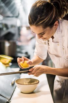 a woman in a white shirt is preparing food on a counter with a knife and bowl