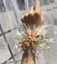 a woman's hand with a white and orange wrist corsage