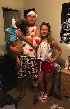 a man and woman dressed up as zombies with a dog in their arms, standing next to each other