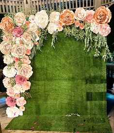 an artificial grass backdrop with flowers and greenery