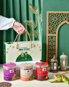 a person holding a shopping bag next to some candles and other items on a table