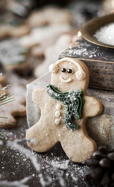 a cookie shaped like a snowman next to a bowl of sugar and pine cones