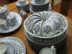 a table topped with lots of blue and white china dishes on top of a wooden table