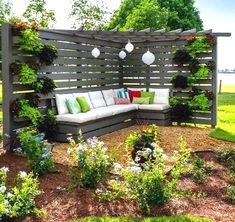 a couch sitting on top of a wooden bench in a garden next to flowers and trees