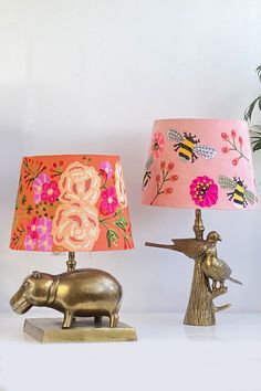 two lamps are sitting on a table next to each other, one with an elephant lamp and the other with a bird figurine