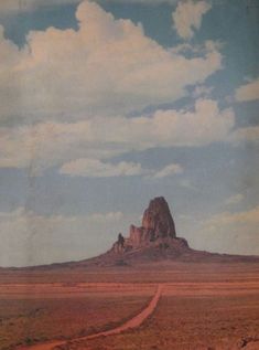 a dirt road in the middle of an open field with a mountain in the background