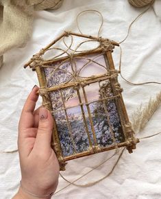 a person holding up a small frame with pictures on it and twine in front of them