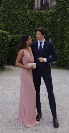 a man in a suit and tie standing next to a woman wearing a pink dress