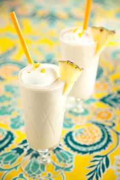 two glasses filled with drinks sitting on top of a colorful table cloth covered in flowers