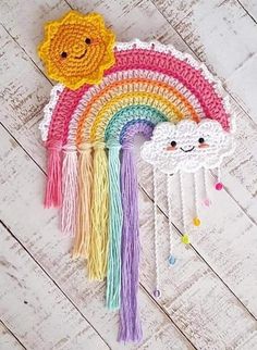 a crocheted rainbow and cloud decoration on a white wood floor with a wooden background