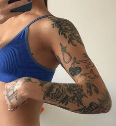 a woman with tattoos on her arm holding a cell phone to her ear and wearing a blue sports bra