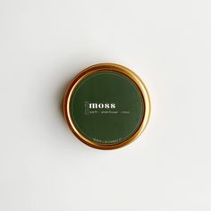 a round tin with the word moss on it sitting on top of a white surface