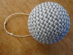 a white and gray ball sitting on top of a wooden table next to a cord