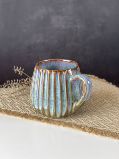 a coffee cup sitting on top of a burlap place mat next to a plant