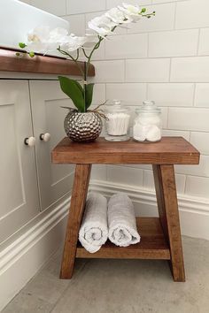 a wooden table topped with white towels next to a vase filled with flowers and candles