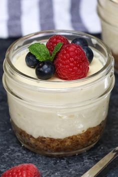 there is a small jar with some food in it and raspberries on top