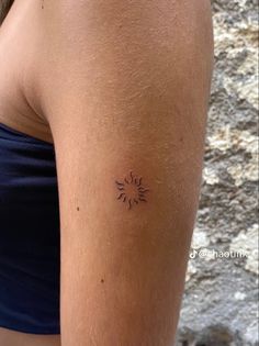 the back of a woman's arm with a small sun tattoo on her left side