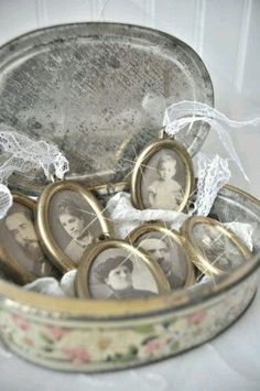 an open tin can filled with small pictures and lace around the edges, sitting on a white table cloth