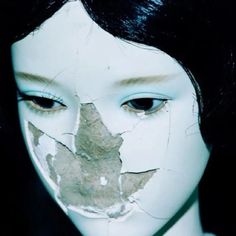 a woman's face with torn paper on it and leaves sticking out of her eyes