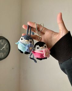 two small crocheted keychains are being held by a person