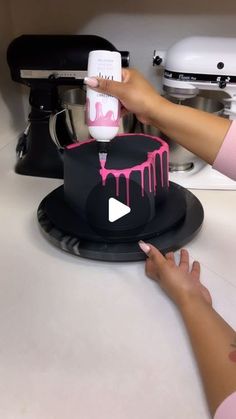 a woman is decorating a cake with pink icing on the top and bottom