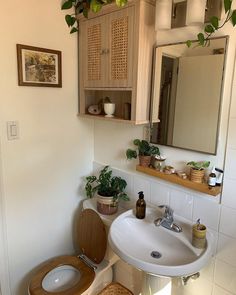 a bathroom with a wooden toilet seat and sink, plants on the wall above it