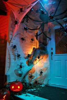 halloween decorations in front of a house with spider webs and pumpkins on the door