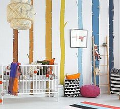 a baby's room with colorful trees painted on the wall and crib in the foreground