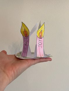 a hand holding up a piece of paper with candles on it